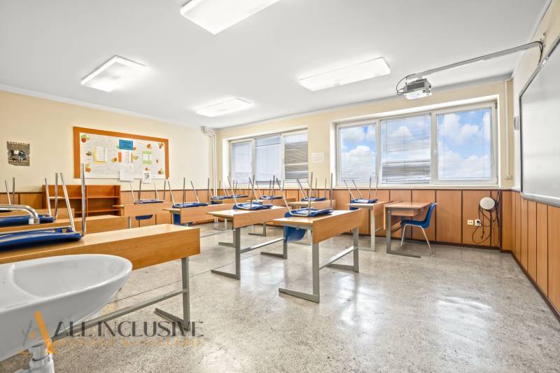 NA PREDAJ ŠKOLSKÁ BUDOVA NA VEĽKOM POZEMKU, MOSTOVÁ - Interiér triedy v budove s oknami, lavicami a stoličkami.