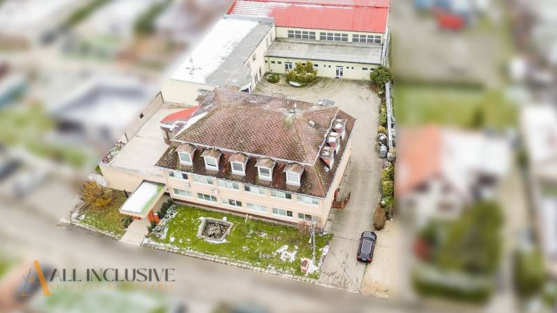 NA PREDAJ ŠKOLSKÁ BUDOVA NA VEĽKOM POZEMKU, MOSTOVÁ - Letecká fotografia budovy v Mostovej so záhradou a asfaltovým parkoviskom v okolí.