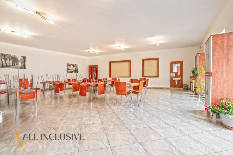 NA PREDAJ ŠKOLSKÁ BUDOVA NA VEĽKOM POZEMKU, MOSTOVÁ - Priestranná jedáleň v budove s dlažbou, kvetinami a obrázkami na stenách.