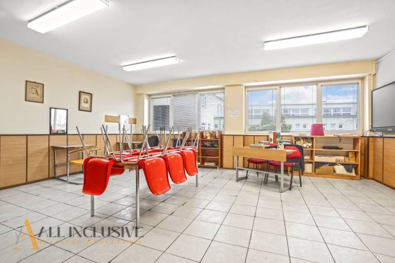NA PREDAJ ŠKOLSKÁ BUDOVA NA VEĽKOM POZEMKU, MOSTOVÁ - V interiéri budovy sa nachádza miestnosť s červenými stoličkami na stole a veľkými oknami.
