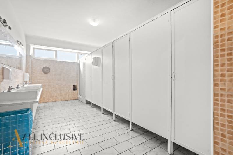 NA PREDAJ ŠKOLSKÁ BUDOVA NA VEĽKOM POZEMKU, MOSTOVÁ - Interiér budovy s radom umývadiel a toaletných kabínok, obklady v béžovej farbe.