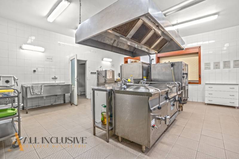 NA PREDAJ ŠKOLSKÁ BUDOVA NA VEĽKOM POZEMKU, MOSTOVÁ - Profesionálna kuchyňa v budove s nerezovým vybavením a bielymi dlaždicami.