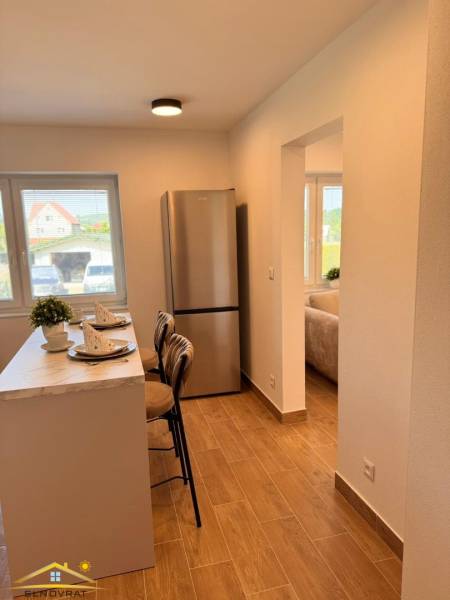 Prenájom: 2 izbový byt v obci Staškov (316-B) - Kuchyňa v 2-izbovom byte s barom, podlahou s dreveným dekorom a chladničkou.