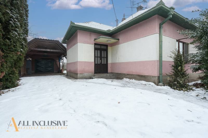 Na predaj 4-izbový rodinný dom, Gabčíkovo - Rodinný dom v Gabčíkove obklopený snehom, vedľa stojí garážový prístrešok.