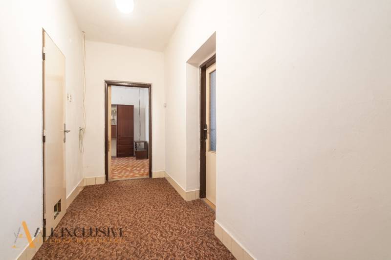 Na predaj 4-izbový rodinný dom, Gabčíkovo - Chodba v rodinnom dome s kobercom, viditeľný vstup do ďalšej miestnosti.