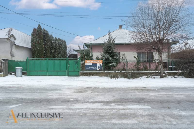 Na predaj 4-izbový rodinný dom, Gabčíkovo - Rodinný dom v Gabčíkove s predajným nápisom a zasneženým okolím.