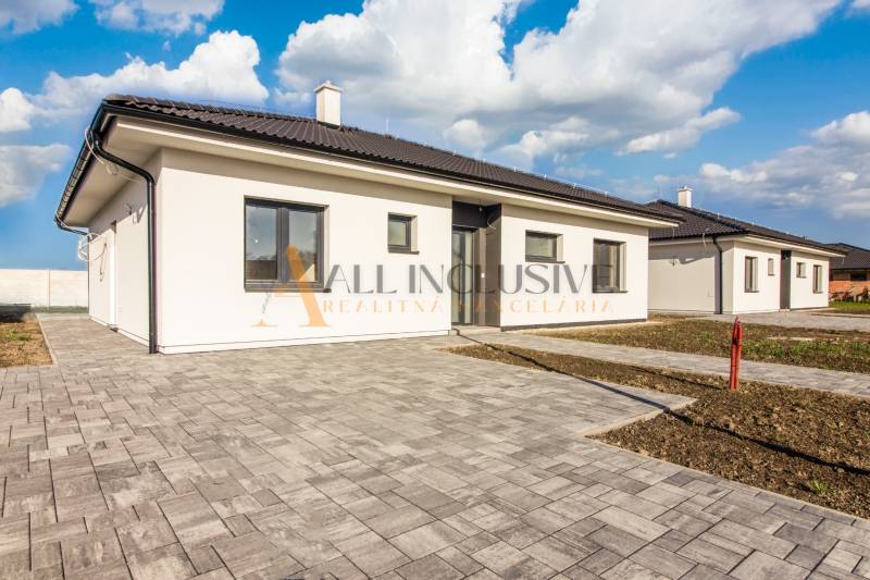 NA PREDAJ 4 IZBOVÝ RODINNÝ DOM-NOVOSTAVBA, KRÁĽOV BROD - Rodinný dom s bielou fasádou, šedou strechou a dláždenou terasou na pozemku.