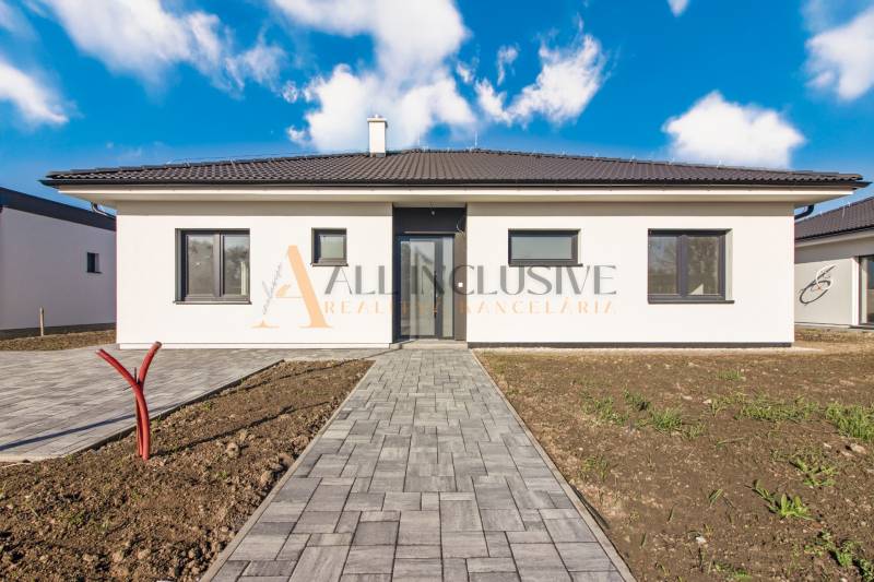 NA PREDAJ 4 IZBOVÝ RODINNÝ DOM-NOVOSTAVBA, KRÁĽOV BROD - Rodinný dom so svetlou fasádou, úpravou okolia a dláždeným chodníkom pod belasou oblohou.