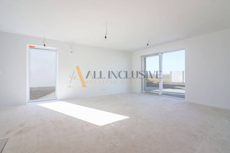 NA PREDAJ 4 IZBOVÝ RODINNÝ DOM-NOVOSTAVBA, KRÁĽOV BROD - Priestranný svetlý interiér s veľkými oknami a bielymi stenami v rodinnom dome.