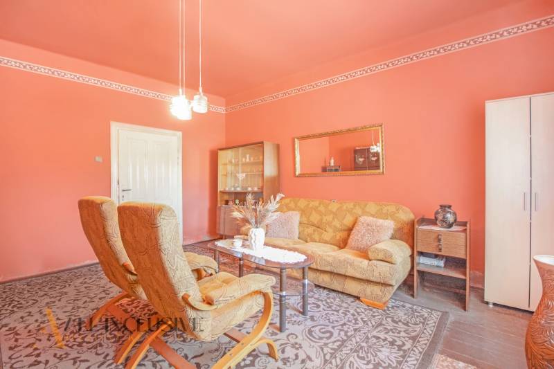 NA PREDAJ 4-IZBOVÝ RODINNÝ DOM NA PRIESTRANNOM POZEMKU - Interiér obývačky s oranžovými stenami, pohodlným nábytkom, lampami a nástenným zrkadlom. Rodinný dom.