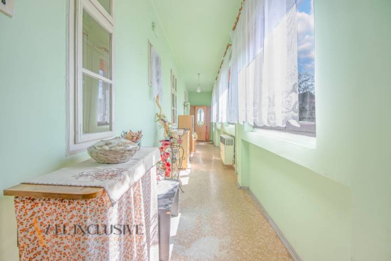 NA PREDAJ 4-IZBOVÝ RODINNÝ DOM NA PRIESTRANNOM POZEMKU - Interiér rodinného domu s chodbou, svetlými stenami a kvetinovou dekoráciou.