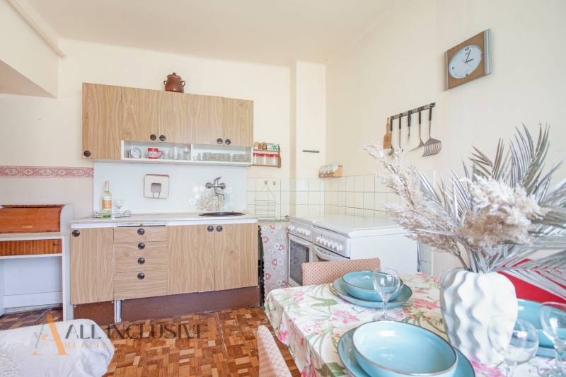 NA PREDAJ 4-IZBOVÝ RODINNÝ DOM NA PRIESTRANNOM POZEMKU - Kuchyňa v rodinnom dome s drevenými skrinkami, stolom a dekoráciou na vidiecku atmosféru.