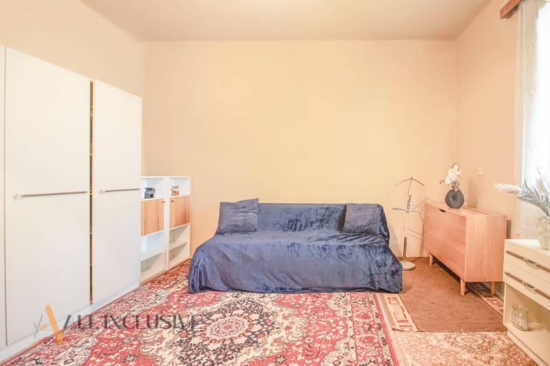 NA PREDAJ 4-IZBOVÝ RODINNÝ DOM NA PRIESTRANNOM POZEMKU - Obývacia izba rodinného domu so sedačkou, kobercom a skriňami, svetlý priestor.