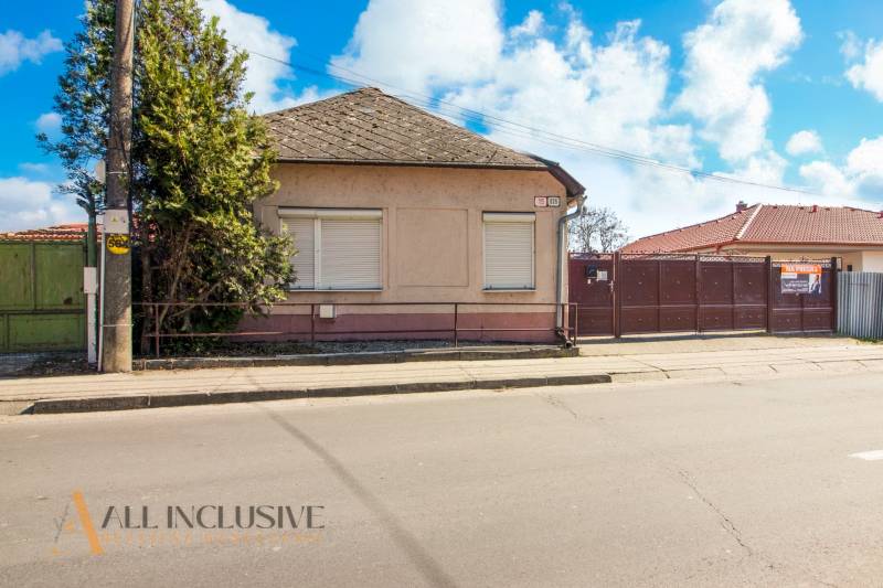 NA PREDAJ 4-IZBOVÝ RODINNÝ DOM NA PRIESTRANNOM POZEMKU - Rodinný dom s plotom, stromom a výveskou na predaj, vhodný na bývanie.