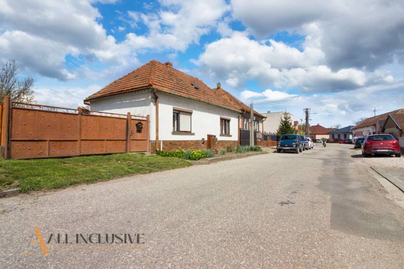 NA PREDAJ RODINNÝ DOM NA 9,5 ÁROVOM POZEMKU, OHRADY - Rodinný dom na ulici Ohrady v Dunajskej Strede s tradičnou strechou a bránou.