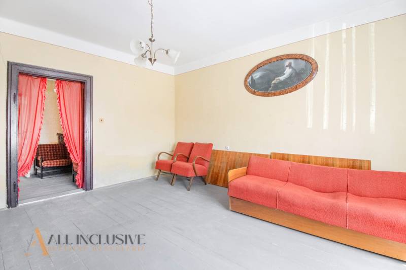 NA PREDAJ RODINNÝ DOM NA 9,5 ÁROVOM POZEMKU, OHRADY - Obývačka v rodinnom dome s oranžovou sedačkou, kreslami, obrázkom a lustrom.