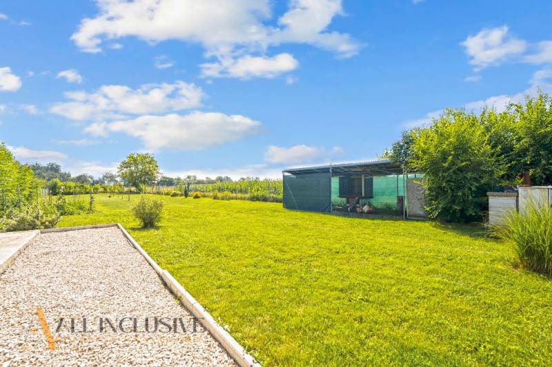 REZERVOVANÉ 3-IZBOVÝ RODINNÝ DOM V OBCI BALOŇ - Záhrada rodinného domu v Baloňi s udržiavaným trávnikom a prístreškom.