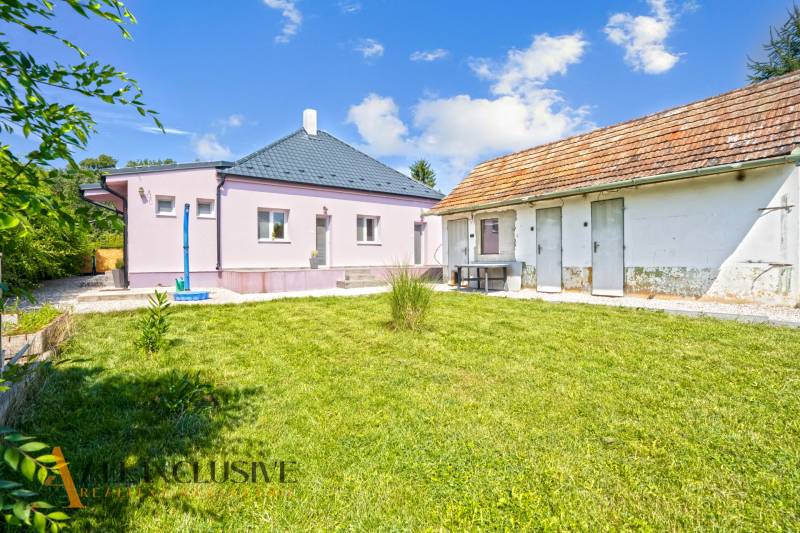 REZERVOVANÉ 3-IZBOVÝ RODINNÝ DOM V OBCI BALOŇ - Rodinný dom v Baloni s trávnatou záhradou, vedľa hospodárske budovy pod modrou oblohou.