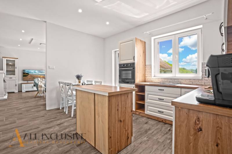 REZERVOVANÉ 3-IZBOVÝ RODINNÝ DOM V OBCI BALOŇ - Kuchyňa rodinného domu s dreveným nábytkom, podlahou s dreveným dekorom a jedálenským stolom.