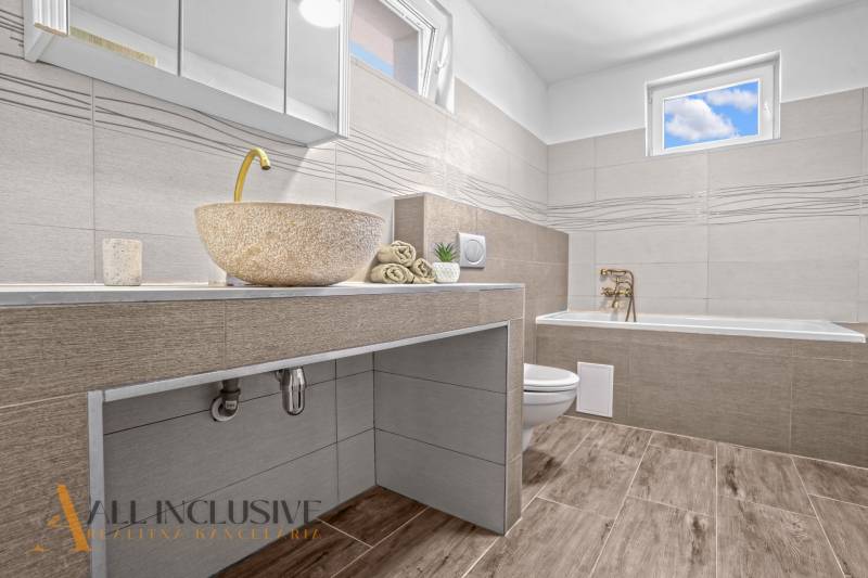 REZERVOVANÉ 3-IZBOVÝ RODINNÝ DOM V OBCI BALOŇ - Kúpeľňa v rodinnom dome s kamenným umývadlom a podlahou s dreveným dekorom.