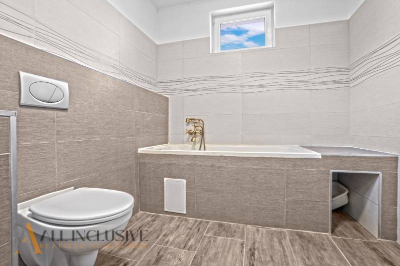 REZERVOVANÉ 3-IZBOVÝ RODINNÝ DOM V OBCI BALOŇ - Kúpeľňa v rodinnom dome s vaňou a toaletou, obklady, podlaha s dreveným dekorom.