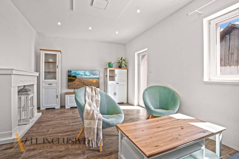 REZERVOVANÉ 3-IZBOVÝ RODINNÝ DOM V OBCI BALOŇ - Obývačka v rodinnom dome s pohodlnými kreslami, stolíkom a podlahou s dreveným dekorom.