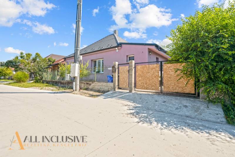 REZERVOVANÉ 3-IZBOVÝ RODINNÝ DOM V OBCI BALOŇ - Rodinný dom v Baloňi s ružovou fasádou, plotom a zelenou vegetáciou v okolí.