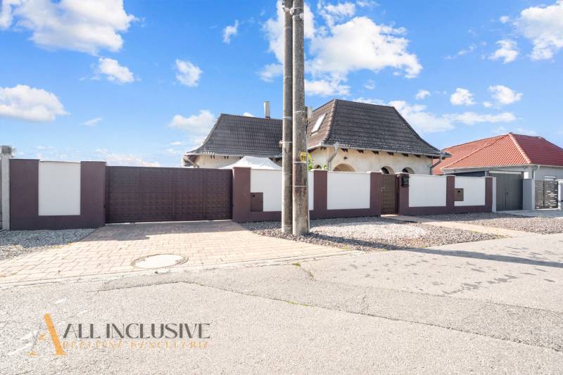 REZERVOVANÉ ZREKONŠTR. 6 IZBOVÝ RODINNÝ DOM, KOŠÚTY - Rodinný dom v Košútoch s bielym plotom a šedou strechou pod modrou oblohou.