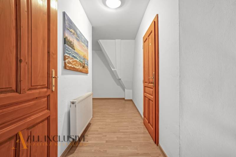 REZERVOVANÉ ZREKONŠTR. 6 IZBOVÝ RODINNÝ DOM, KOŠÚTY - Chodba s drevenými dverami, radiátorom a obrazom, v rodinnom dome s podlahou s dreveným dekorom.