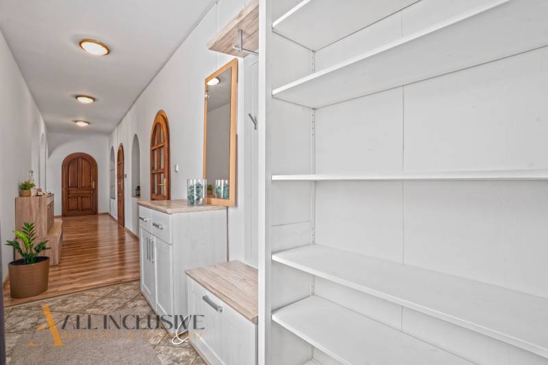 REZERVOVANÉ ZREKONŠTR. 6 IZBOVÝ RODINNÝ DOM, KOŠÚTY - Chodba rodinného domu s policami, podlahou s dreveným dekorom a rastlinou.