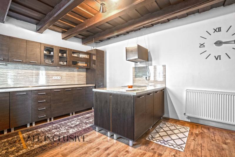 REZERVOVANÉ ZREKONŠTR. 6 IZBOVÝ RODINNÝ DOM, KOŠÚTY - Kuchyňa v rodinnom dome s dreveným stropom, tmavými skrinkami a podlahou s dreveným dekorom.