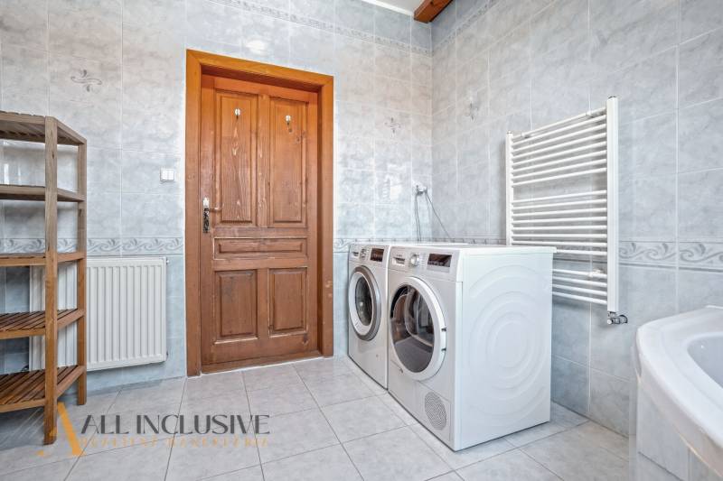 REZERVOVANÉ ZREKONŠTR. 6 IZBOVÝ RODINNÝ DOM, KOŠÚTY - Práčka, sušička, drevené poličky a radiator v kúpeľni rodinného domu.