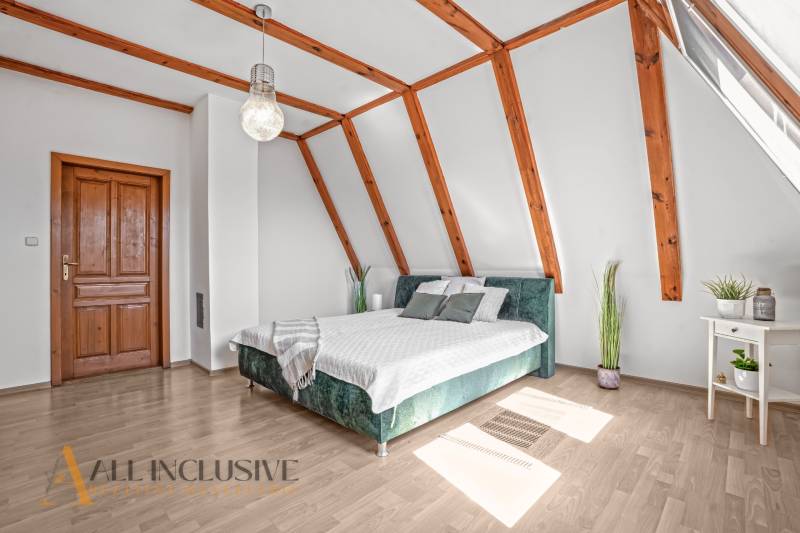 REZERVOVANÉ ZREKONŠTR. 6 IZBOVÝ RODINNÝ DOM, KOŠÚTY - Svetlá spálňa s posteľou, drevenými trámami a podlahou s dreveným dekorom v rodinnom dome.