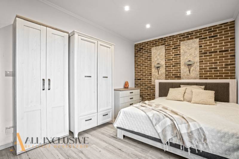 NA PREDAJ 4-IZB NOVOSTAVBA S TROJGARÁŽOU, PIN. KRAČANY - Spálňa v rodinnom dome s posteľou, bielymi skriňami a tehlovou stenou.