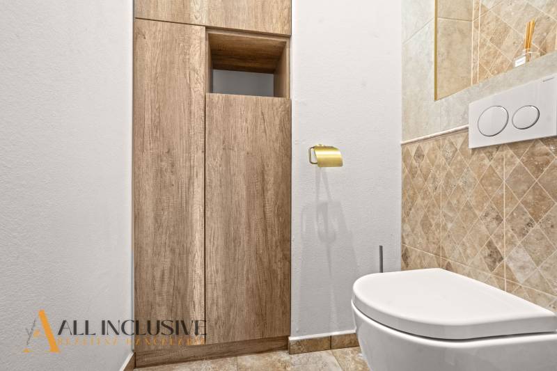 NA PREDAJ 4-IZB NOVOSTAVBA S TROJGARÁŽOU, PIN. KRAČANY - Toaleta v rodinnom dome s podlahou s dreveným dekorom a obkladom do polovice steny.