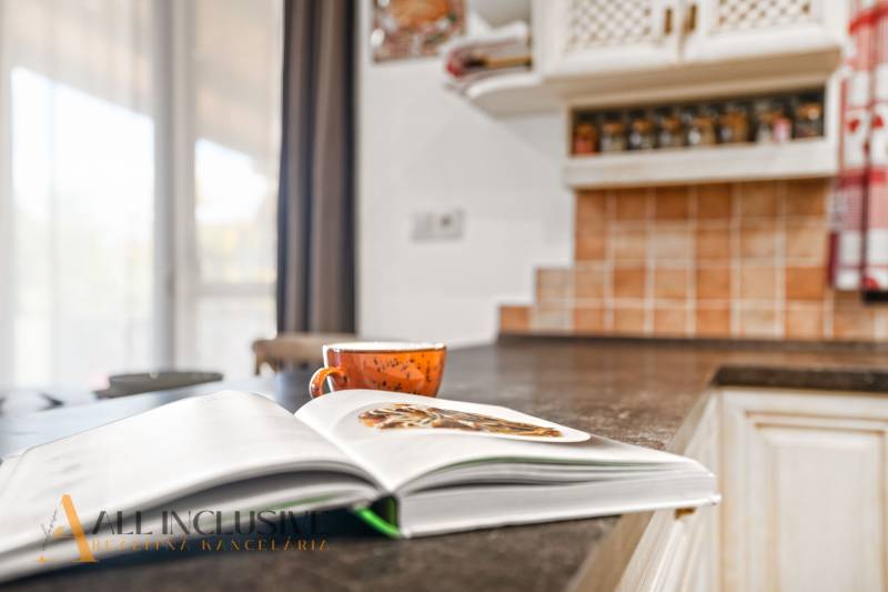 NA PREDAJ 4-IZB NOVOSTAVBA S TROJGARÁŽOU, PIN. KRAČANY - Otvorená kniha a šálka na kuchynskej linke v rodinnom dome.