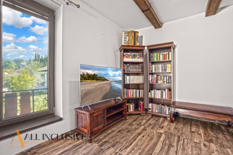 NA PREDAJ 4-IZB NOVOSTAVBA S TROJGARÁŽOU, PIN. KRAČANY - Obývacia izba v rodinnom dome s TV, knihovňou a podlahou s dreveným dekorom.