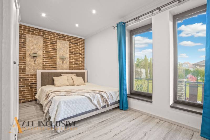 NA PREDAJ 4-IZB NOVOSTAVBA S TROJGARÁŽOU, PIN. KRAČANY - Spálňa v rodinnom dome s tehlovou stenou a výhľadom cez veľké okná.