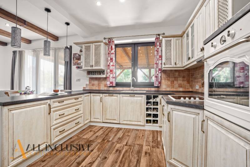 NA PREDAJ 4-IZB NOVOSTAVBA S TROJGARÁŽOU, PIN. KRAČANY - Kuchyňa v rodinnom dome s dreveným dekorom a béžovými skrinkami, svetlé a útulné.