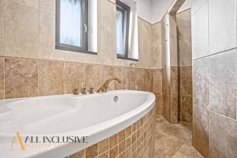 NA PREDAJ 4-IZB NOVOSTAVBA S TROJGARÁŽOU, PIN. KRAČANY - Kúpeľňa v rodinnom dome s veľkou vaňou a obkladačkami v drevenom dekore.