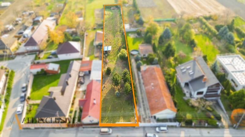 NA PREDAJ STAVEBNÝ POZEMOK (1524 m²), VYDRANY - Letecký pohľad na dlhý pozemok určený na bývanie vo Vydranoch, obklopený domami a zeleňou.