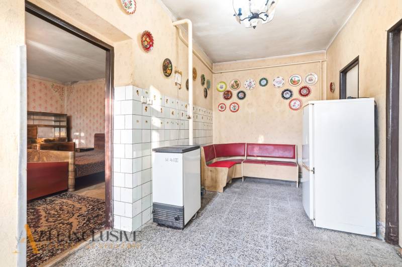 Na predaj 4-izbový rodinný dom, Dolné Saliby - Interiér rodinného domu s červenou rohovou lavicou, dlaždicami a ozdobnými taniermi na stenách.