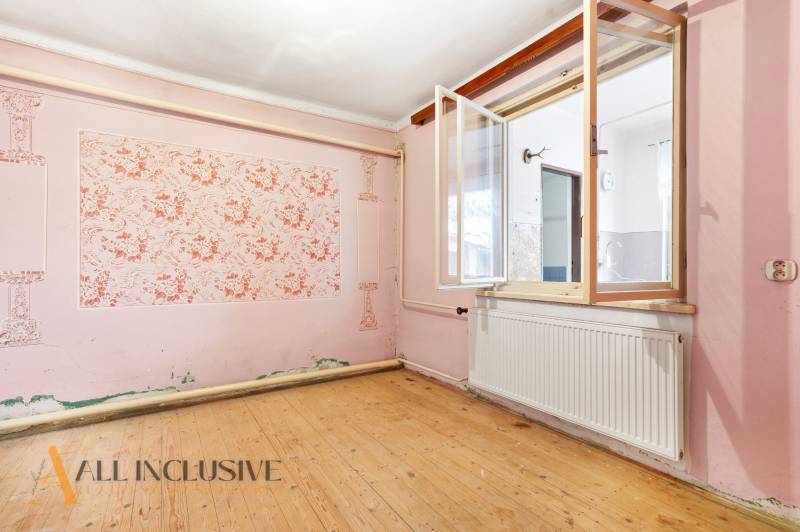 Na predaj 3-izbový rodinný dom, Dobrohošť - Izba v rodinnom dome s podlahou s dreveným dekorom a ružovými stenami.