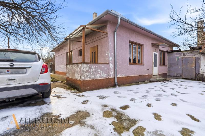 Na predaj 3-izbový rodinný dom, Dobrohošť - Rodinný dom v Dobrohošti s autom zaparkovaným na zasneženom dvore.