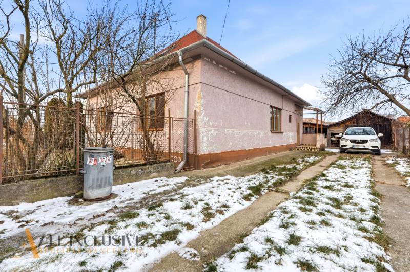 Na predaj 3-izbový rodinný dom, Dobrohošť - Rodinný dom v Dobrohošti s autom na zasneženom dvore a stromami v záhrade.