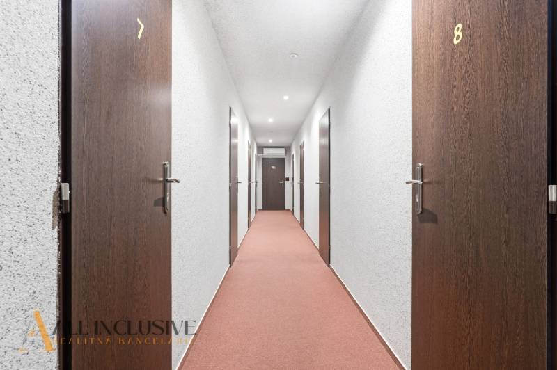 Na prenájom podnikateľské priestory, Senec - Hotelová chodba s číslovanými dverami a červeným kobercom.