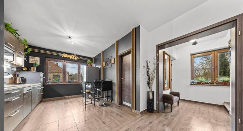 Na predaj 5-izb. rodinný dom na 50-á pozemku, Sap - Kuchyňa v rodinnom dome s podlahou s dreveným dekorom a veľkými oknami.