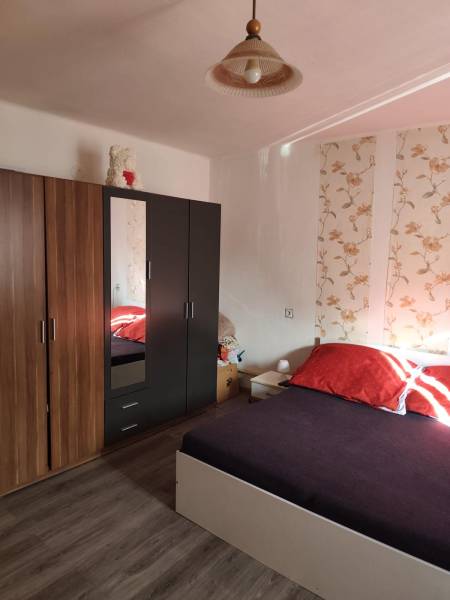 Na predaj 3-izb. rodinný dom, Gabčíkovo – Polná ulica - Spálňa v rodinnom dome s posteľou, vzorovanou tapetou, skrinkou a podlahou s dreveným dekorom.