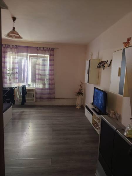 Na predaj 3-izb. rodinný dom, Gabčíkovo – Polná ulica - Obývacia izba v Rodinnom dome s podlahou s dreveným dekorom, televízorom a záclonami.