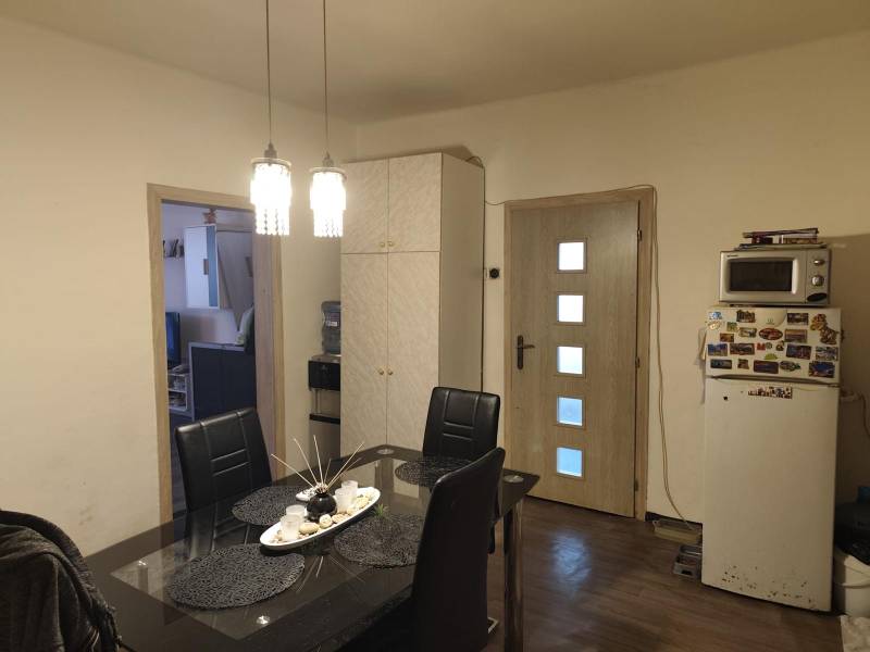 Na predaj 3-izb. rodinný dom, Gabčíkovo – Polná ulica - Jedáleň v rodinnom dome s čiernym stolom, stoličkami a podlahou s dreveným dekorom.